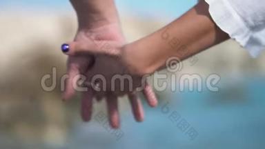 在阳光明媚的海滩上，一对迷人的夫妇紧紧地挽着手走着。 联盟，关爱伙伴.. 慢动作